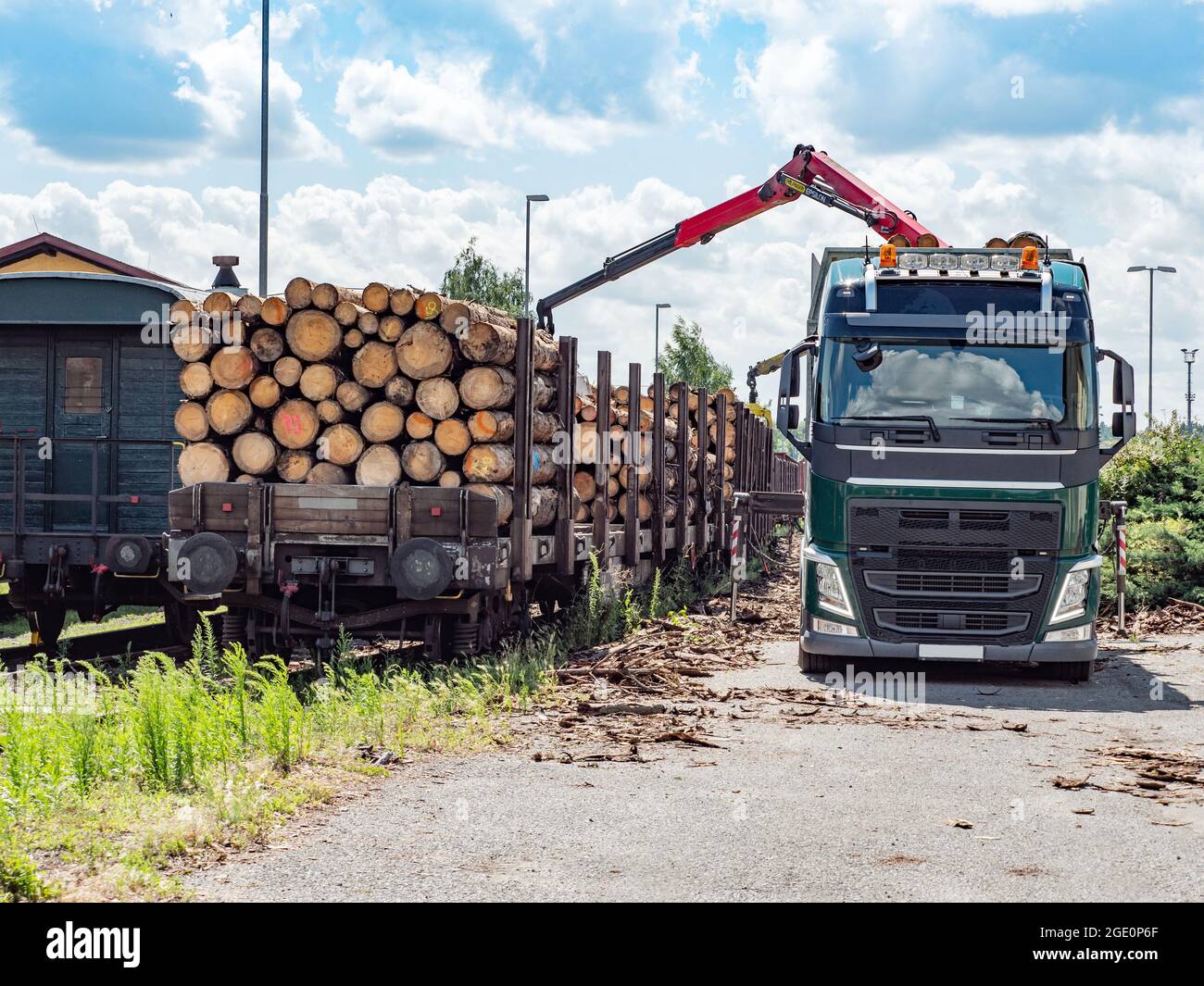 Big truck with crane arm loading the wood logs train. Cranes at
