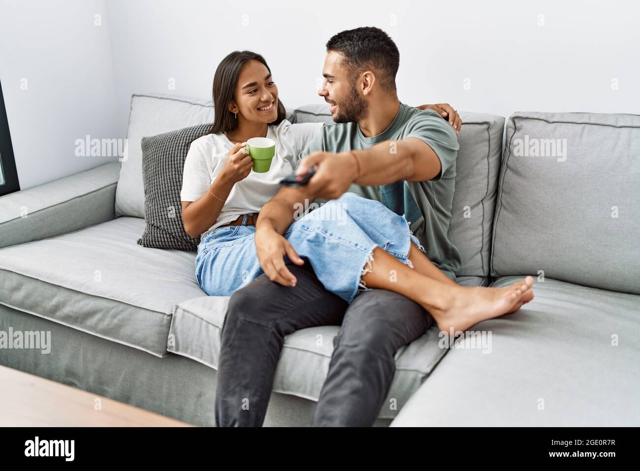Young latin couple smiling happy sitting on the sofa at living room ...
