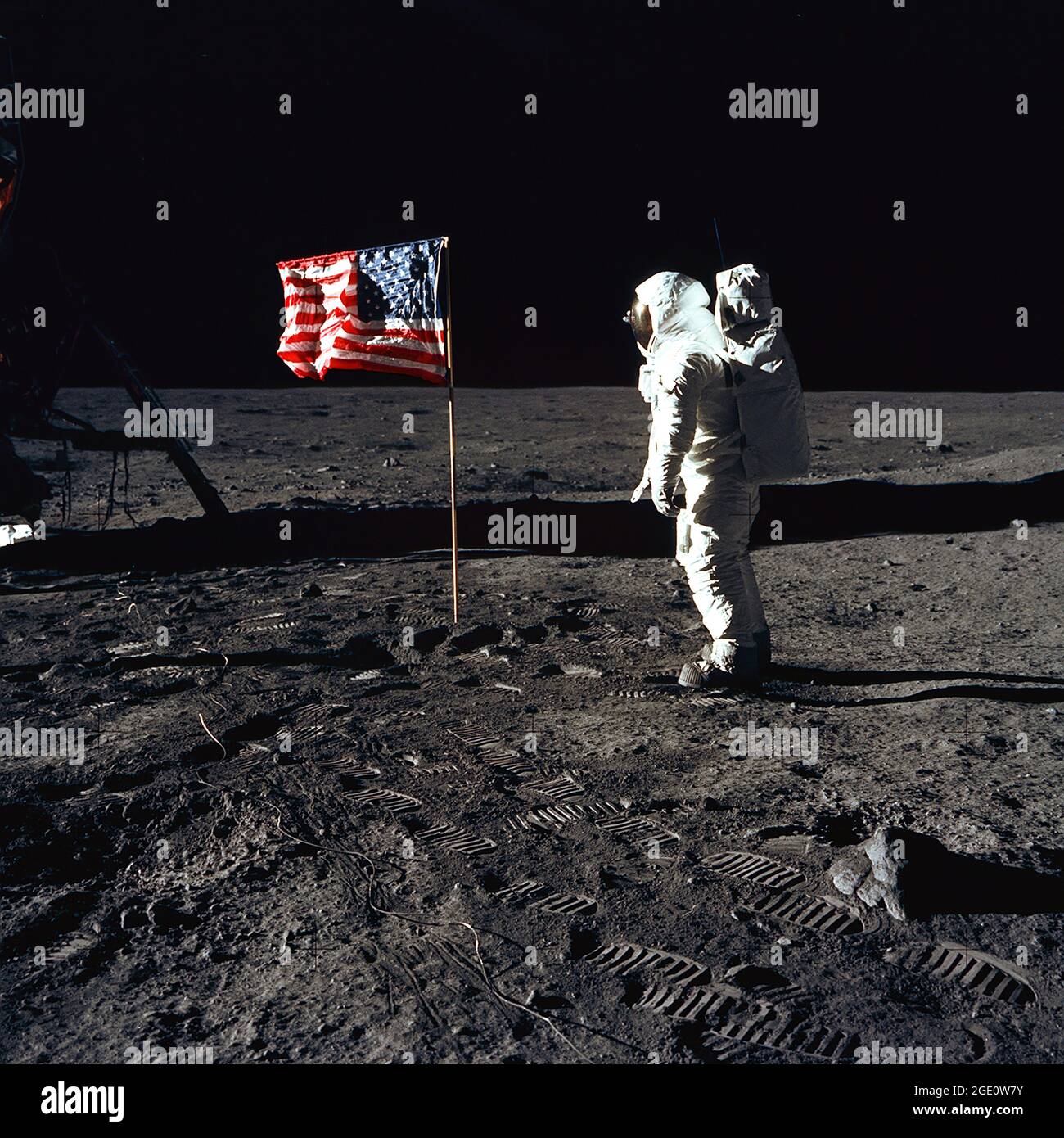 Astronaut Buzz Aldrin, lunar module pilot of the first lunar landing mission, poses for a photograph beside the deployed United States flag during an Apollo 11 Extravehicular Activity (EVA) on the lunar surface. The Lunar Module (LM) is on the left, and the footprints of the astronauts are clearly visible in the soil of the Moon. Astronaut Neil A. Armstrong, commander, took this picture with a 70mm Hasselblad lunar surface camera. While astronauts Armstrong and Aldrin descended in the LM, the 'Eagle', to explore the Sea of Tranquility region of the Moon, astronaut Michael Collins. Stock Photo