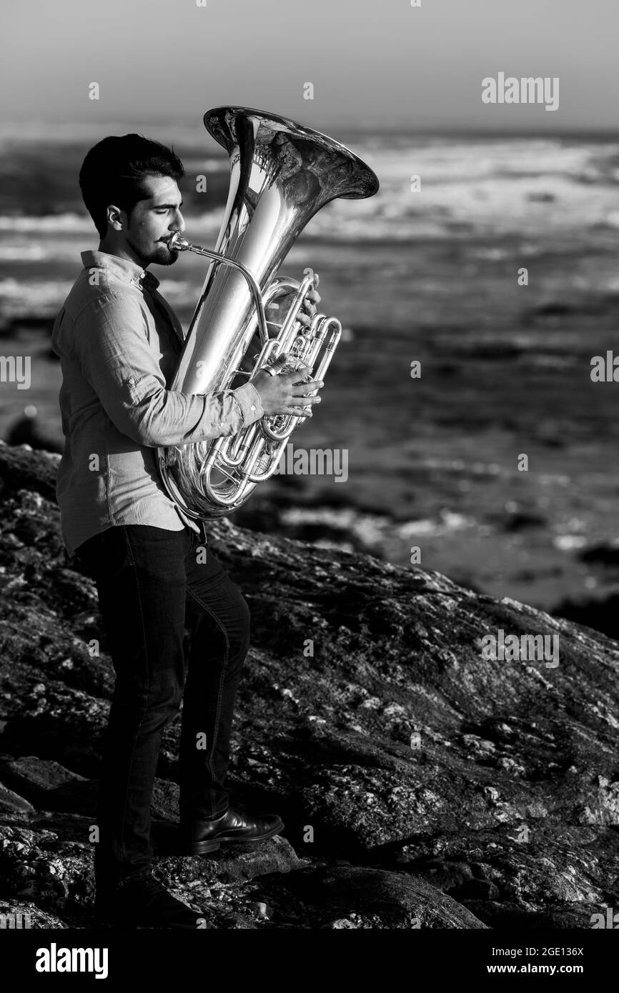 A man musician play a tuba on the seashore. Black and white photo. Stock Photo