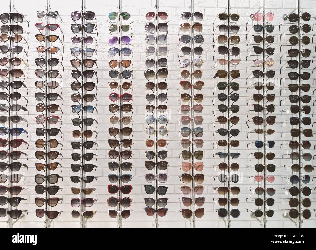 Many sunglasses in eyewear store, display on white wall background Stock Photo