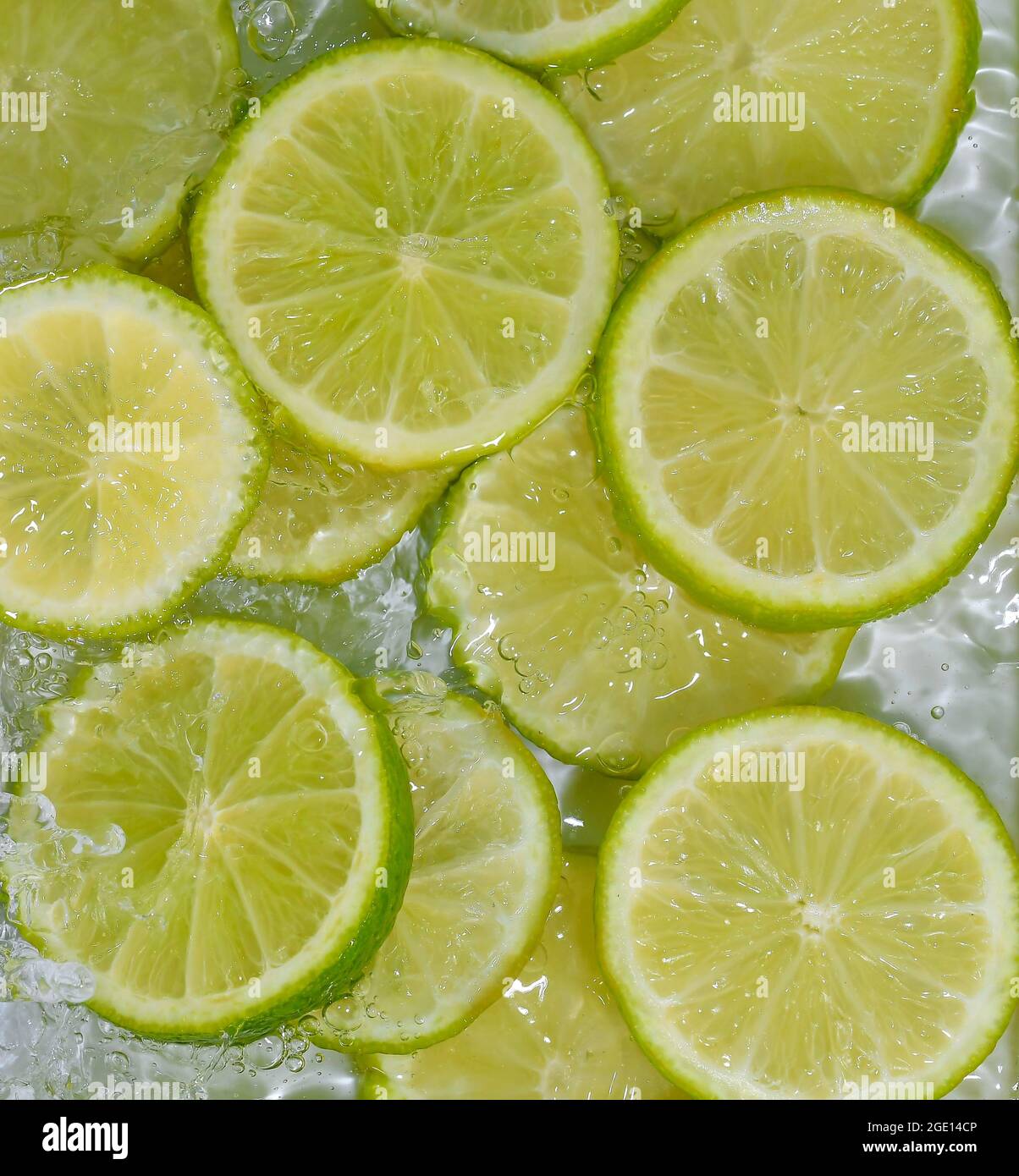 Limes close-up in liquid with bubbles. Slices of green ripe limes in ...