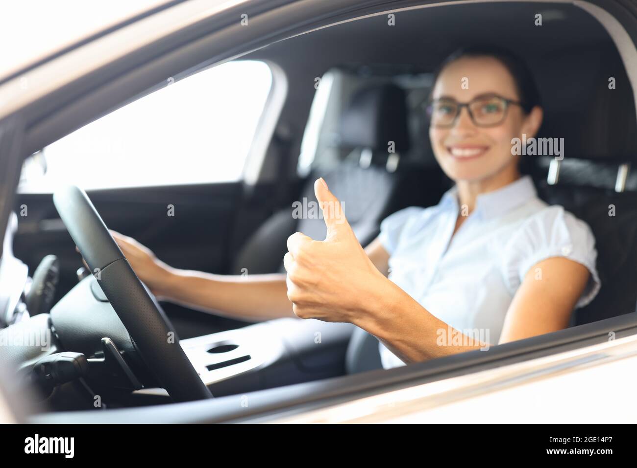 Woman sitting behind wheel of car and showing thumb up closeup Stock ...