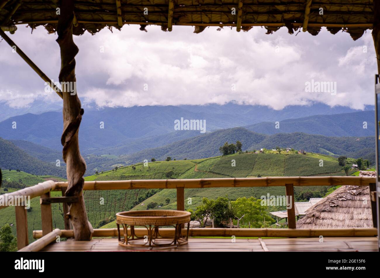 A wooden cottage on top of the hill against a mountainscape under a cloudy sky Stock Photo
