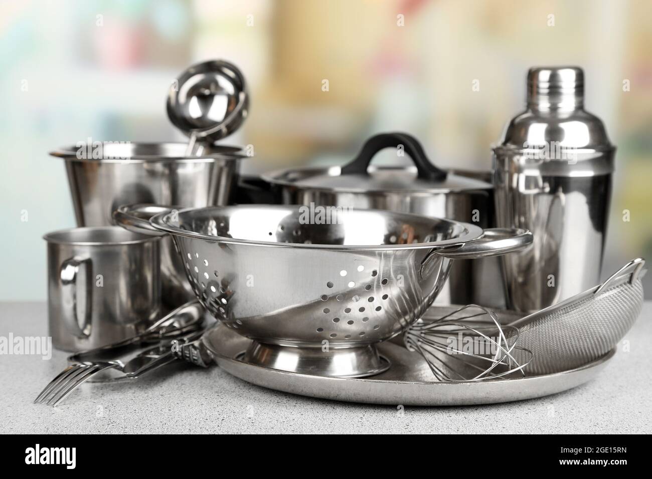Stainless steel kitchenware on table, on light background Stock Photo ...
