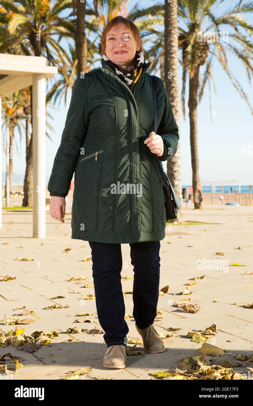 Full-length portrait of woman walking along embankment Stock Photo - Alamy