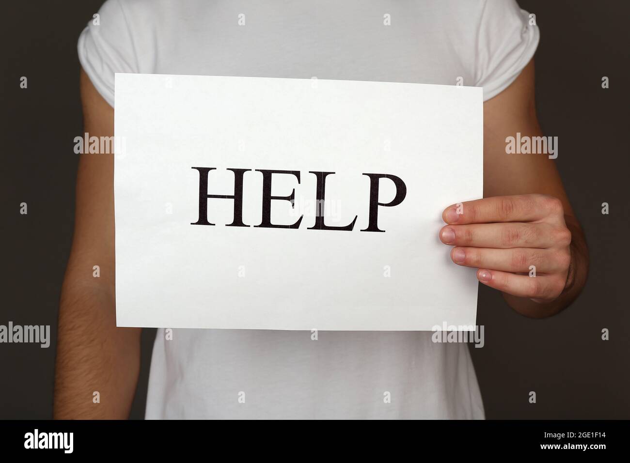 Sheet of paper with Help sign in male hand on dark background Stock ...