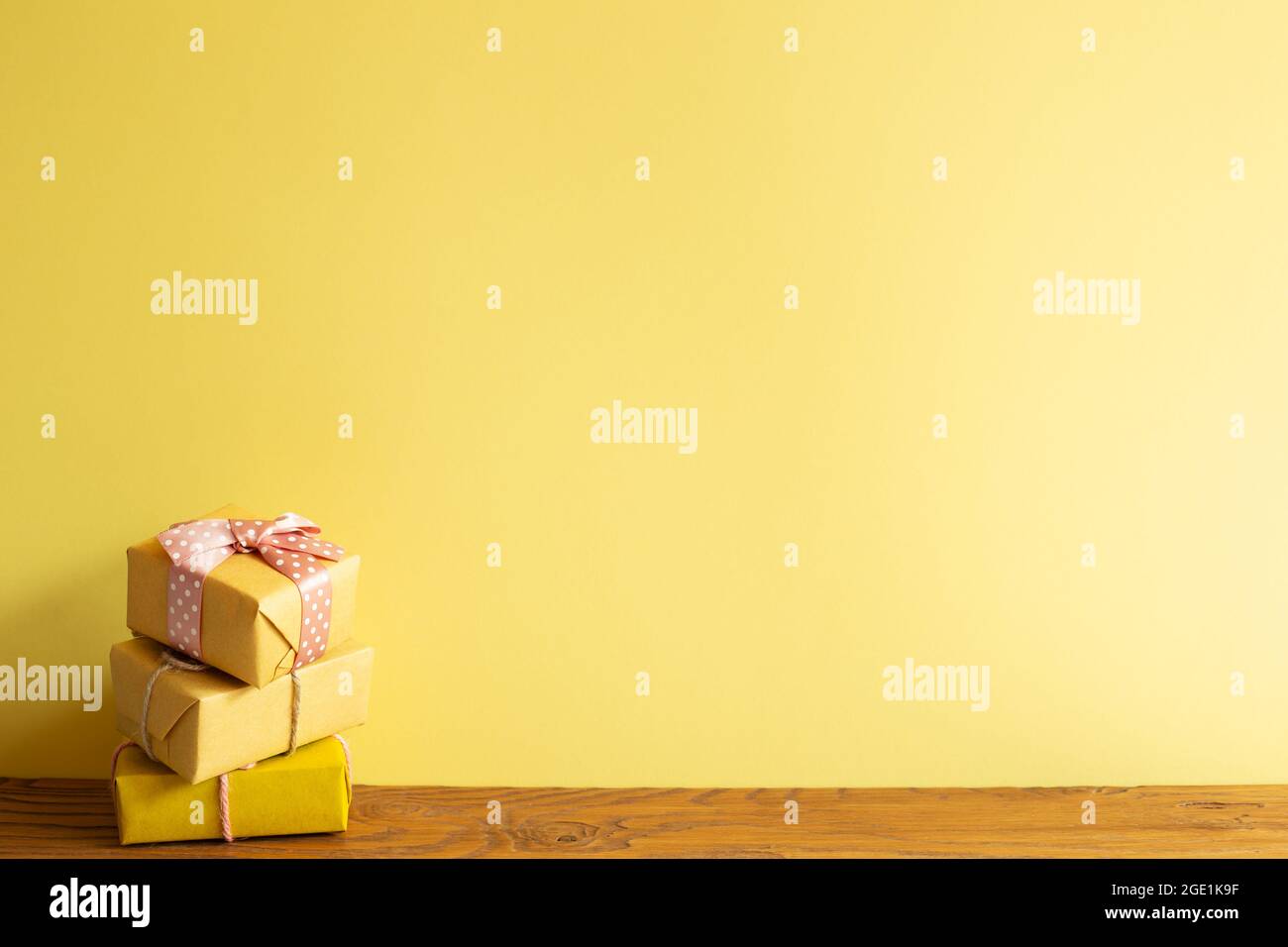 Stack of yellow gift boxes on wooden table. yellow wall background Stock Photo