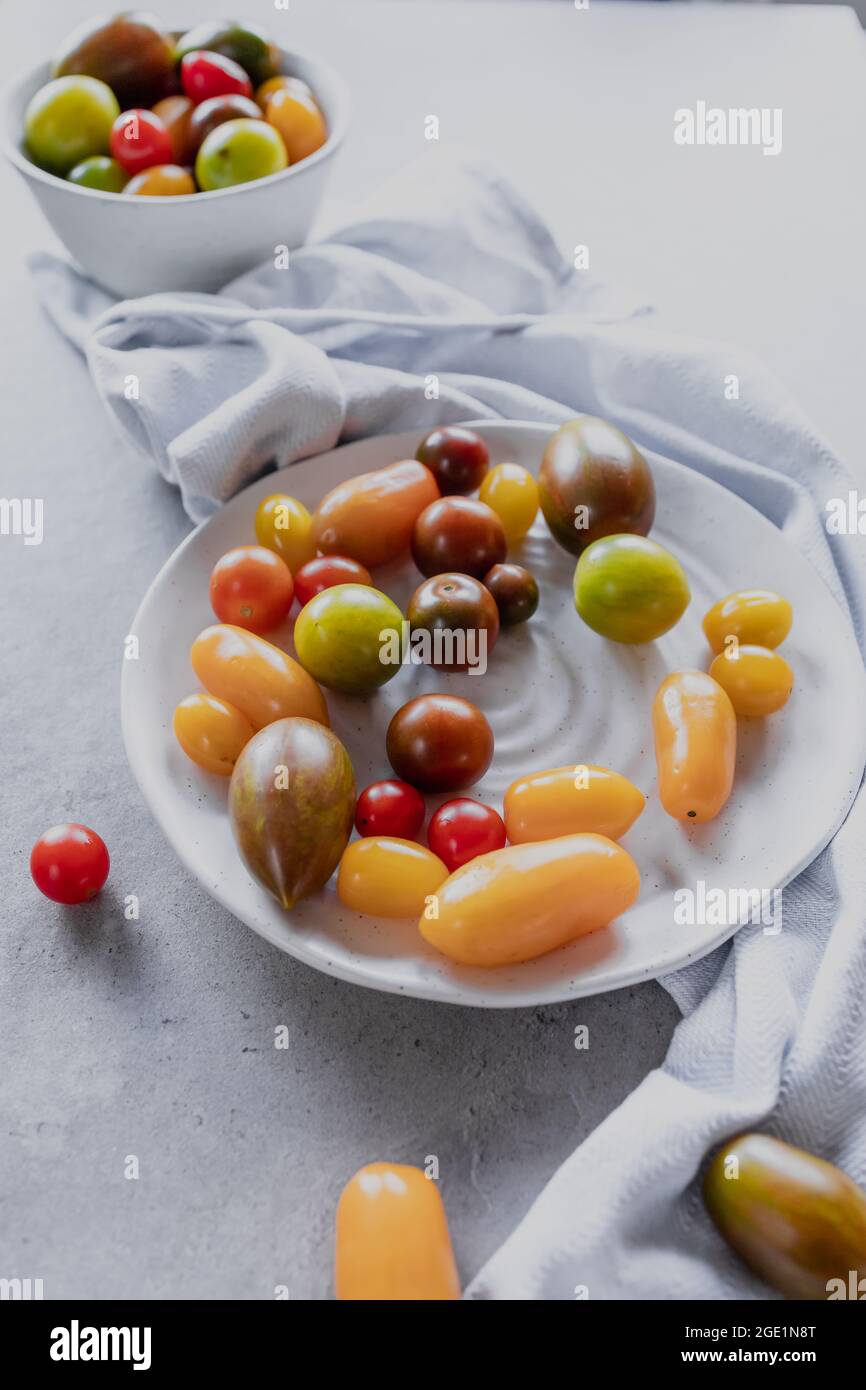 Variety of Coloured cherry tomatoes in a bowl on a grey background, flatlay Stock Photo