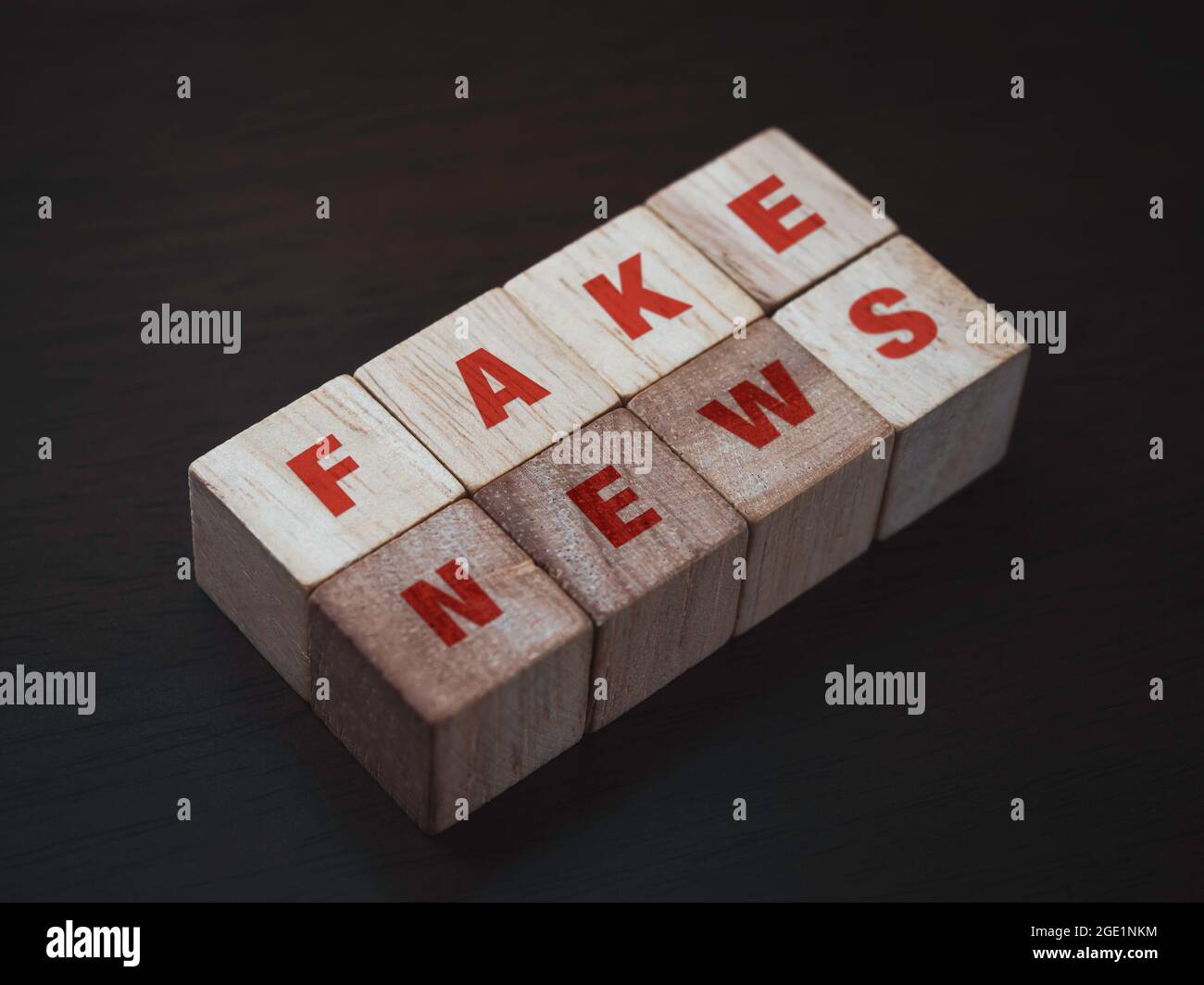 Fake news, red words on wooden cube block on dark background. Fake, discredit, lie, confusion, incite and distortion concept. Stock Photo
