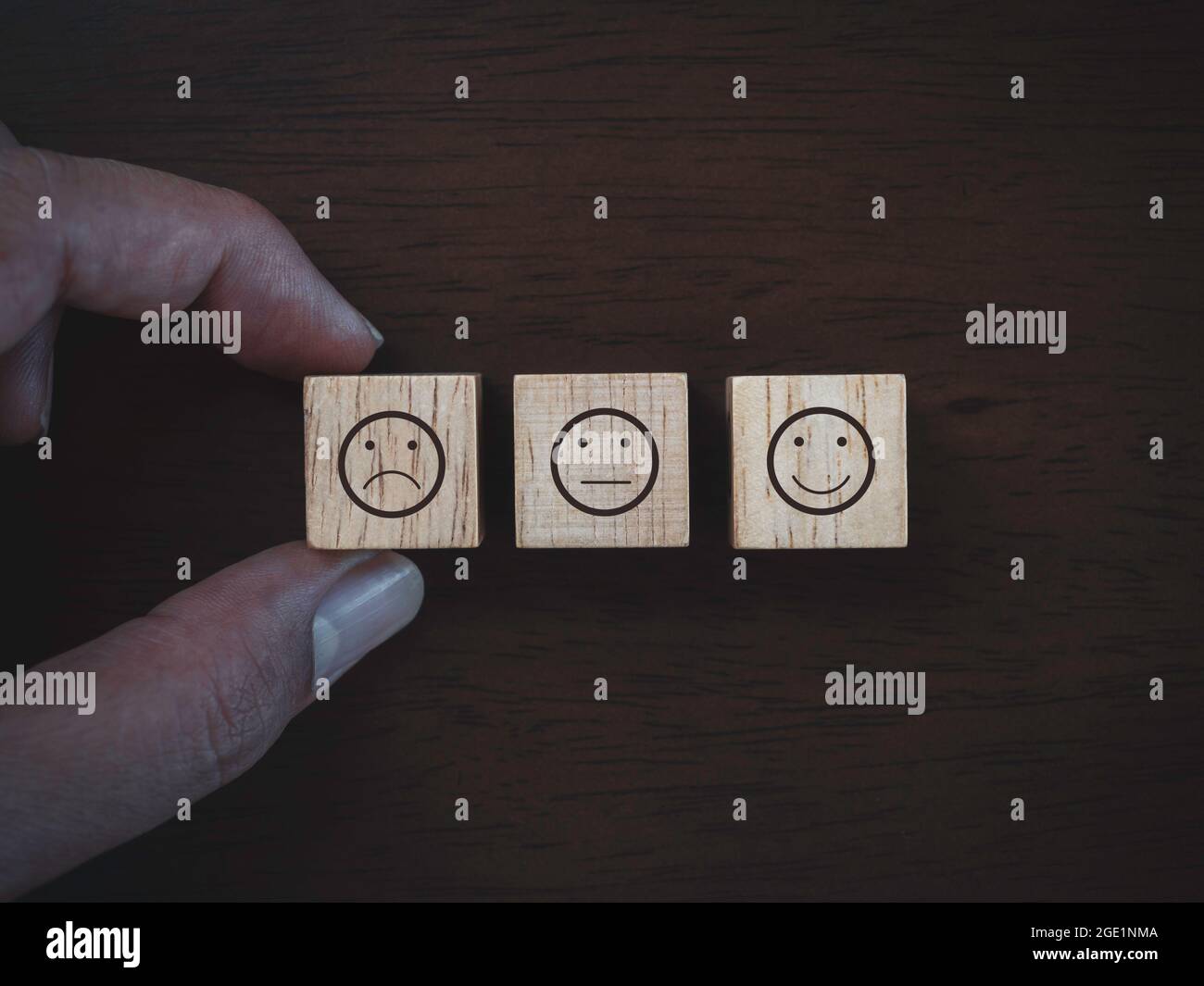 Services rating, ranking, review, feedback and customer satisfaction survey concept. close up finger choosing not satisfied face emoticon icon on wood Stock Photo