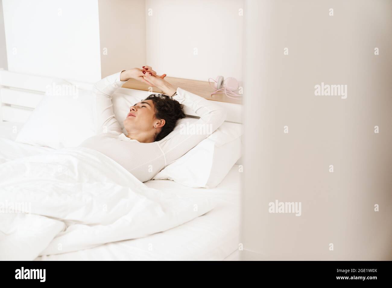The woman with closing eyes while sleeping with raising arms on white