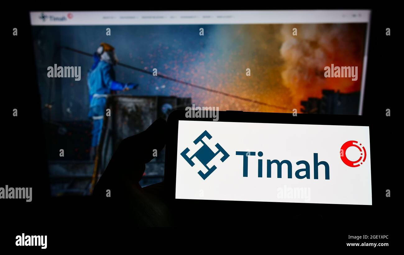 Person holding smartphone with logo of Indonesian tin mining company PT Timah Tbk on screen in front of website. Focus on phone display. Stock Photo