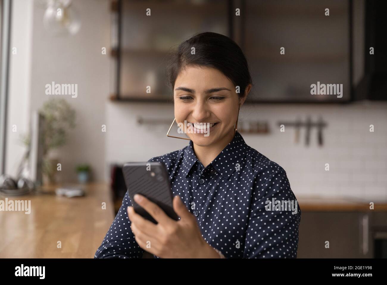 Attractive smiling Indian woman looks at smart phone screen Stock Photo