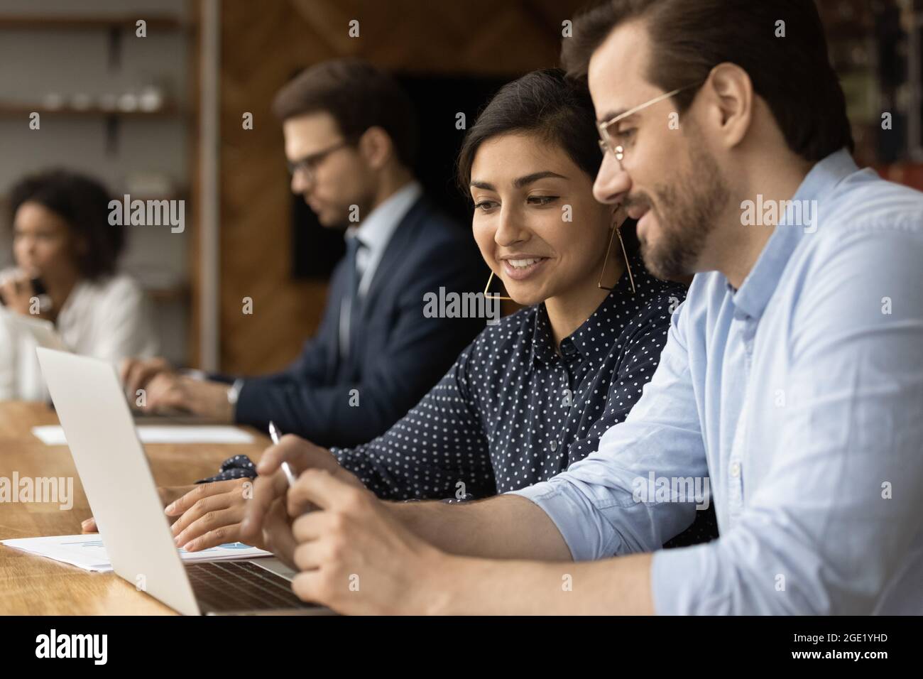 Indian businesswoman caucasian businessman using laptop discussing new collaborative project Stock Photo