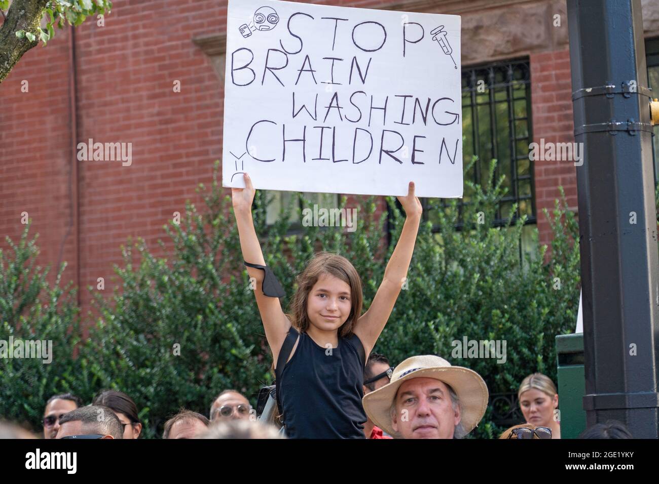 A girl holds a sign that says stop brain washing children during a Republicans Rally against COVID vaccine mandates outside Gracie Mansion in New York City.NYC vaccine mandate starts Monday, August 16th; Proof of coronavirus (COVID-19) vaccination will be required to attend indoor restaurants, gyms, and entertainment venues with enforcement of the mandate to begin on September 13th. (Photo by Ron Adar / SOPA Images/Sipa USA) Stock Photo