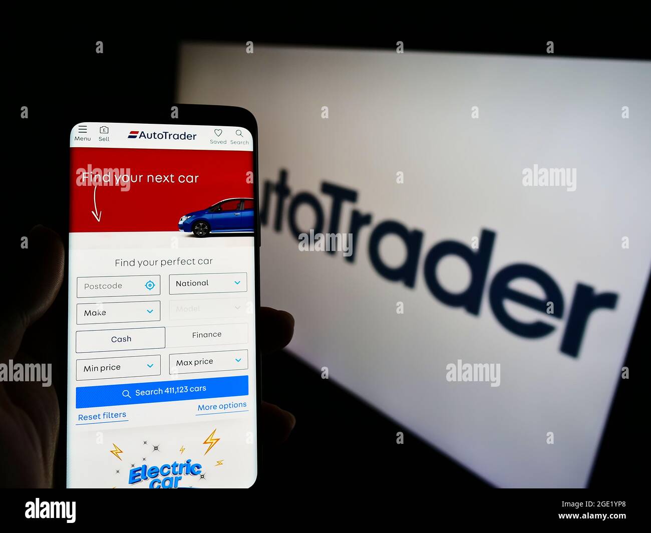 Person holding cellphone with webpage of US online car marketplace Autotrader.com Inc. on screen in front of logo. Focus on center of phone display. Stock Photo