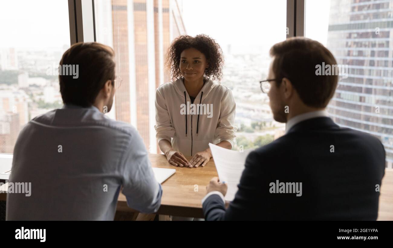 Rear back view HR male managers interviewing African female applicant ...