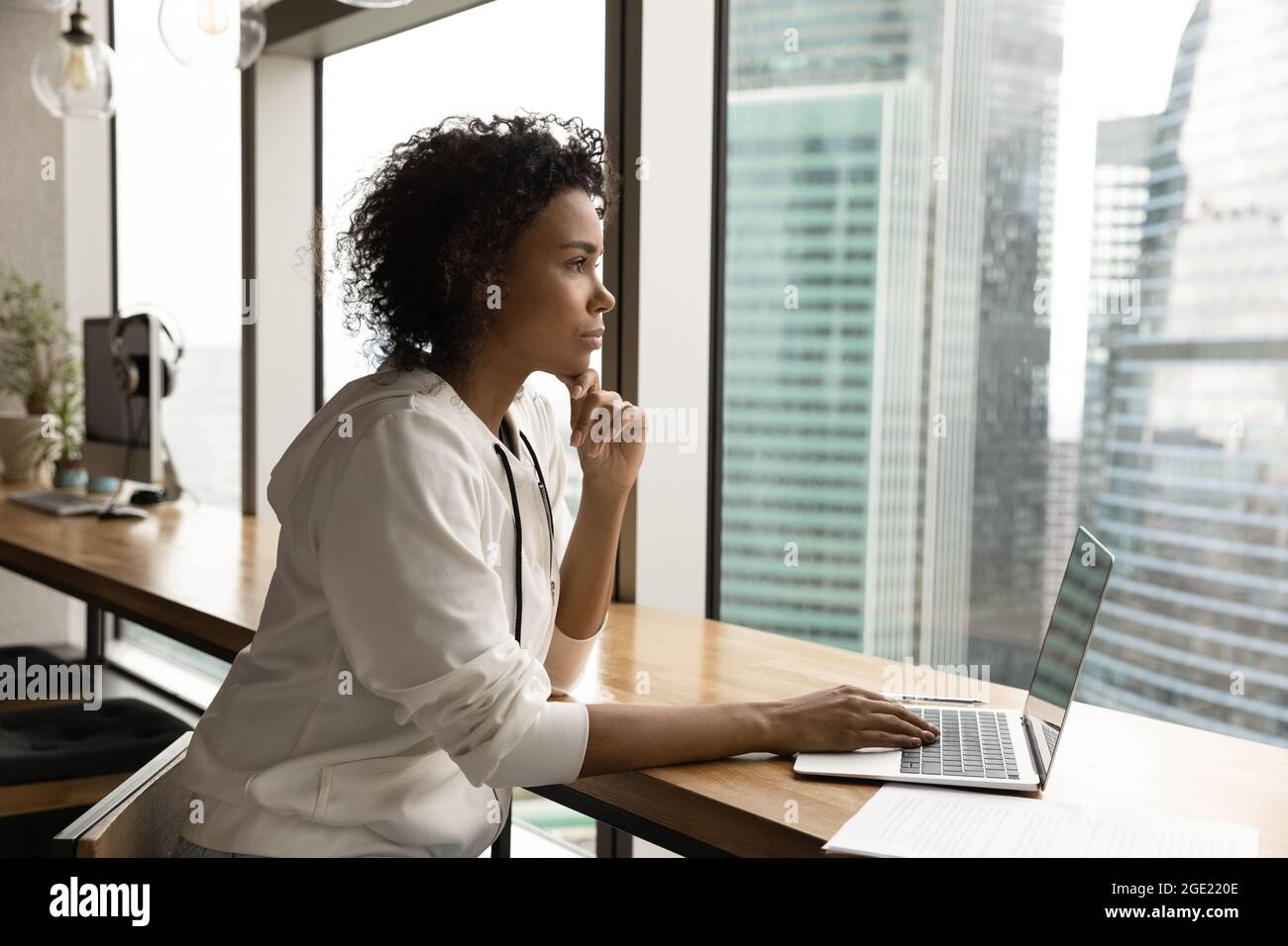 Thoughtful African businesswoman working on computer looking at big city Stock Photo