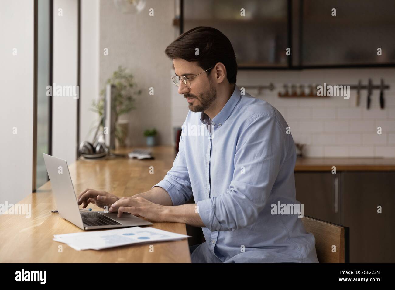 Serious male entrepreneur sit at table working using laptop Stock Photo
