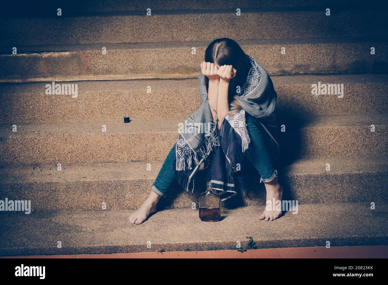 Young drunk woman sitting outside in night. Alcoholism and drug addiction lead to depression. Stock Photo