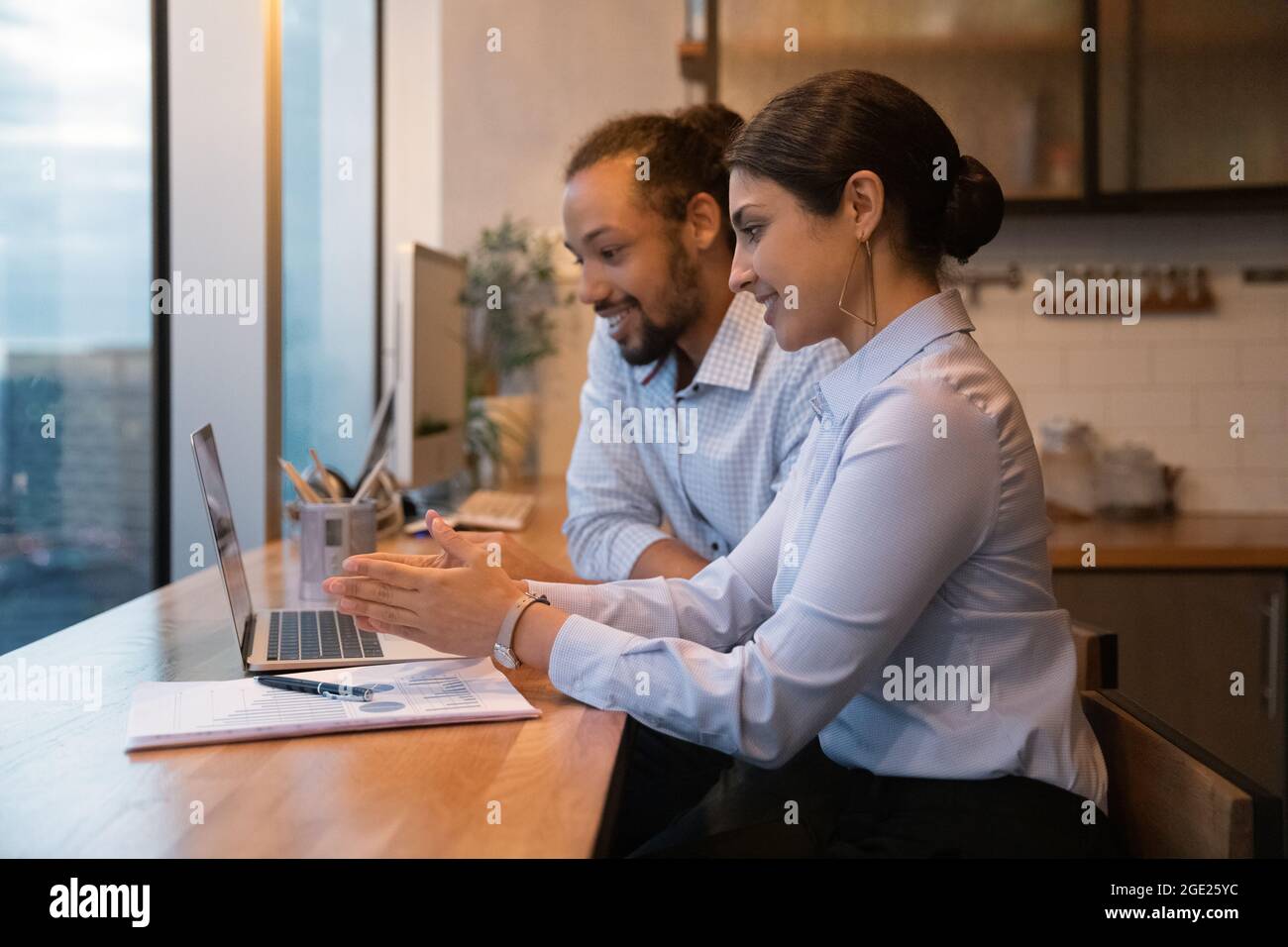Multiracial colleagues sit in modern office kitchen working use laptop Stock Photo