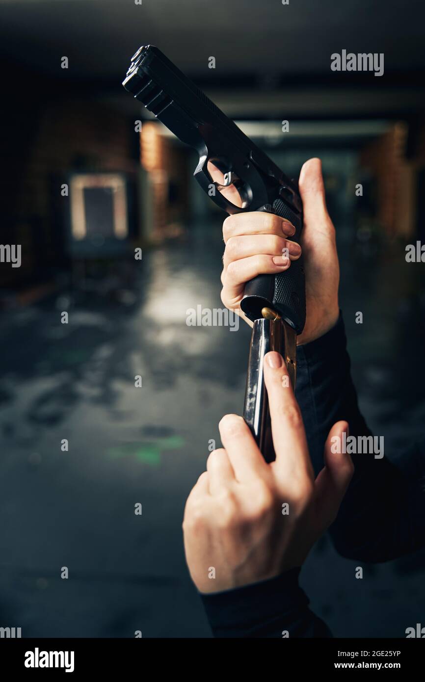 Woman military loading a pistol before a shooting drill Stock Photo