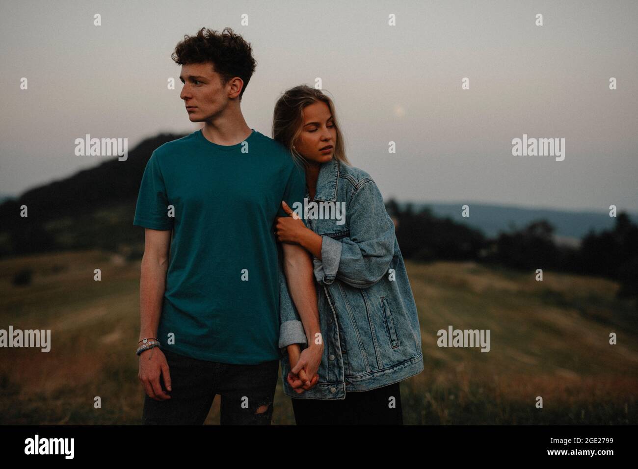 Young couple standing in nature in countryside, holding hands but