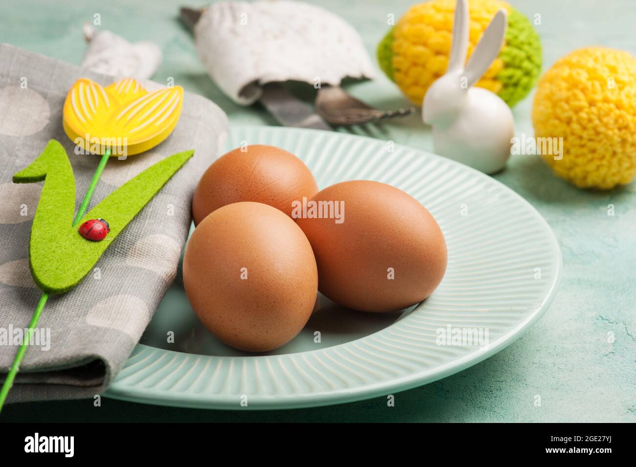 Easter composition with plate, eggs, decorative rabbit on blue cocnrete background Stock Photo