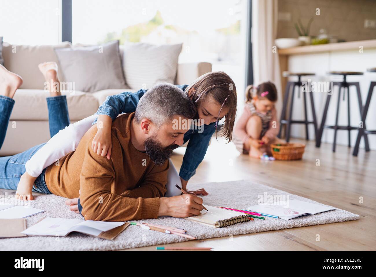 Father with daughters indoors at home, drawing pictures on floor Stock ...