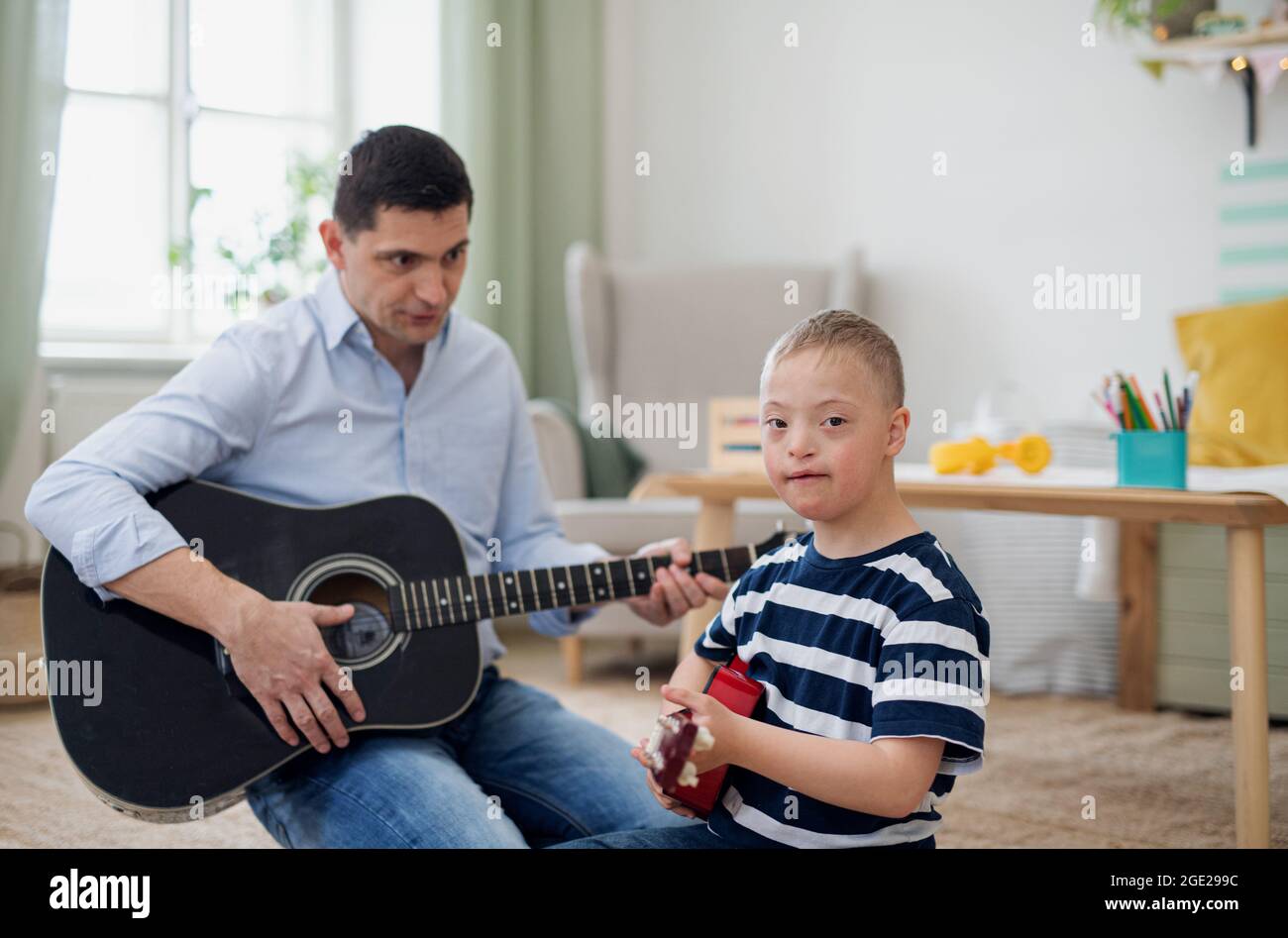 Cheerful down syndrome boy with father playing musical instruments, laughing. Stock Photo