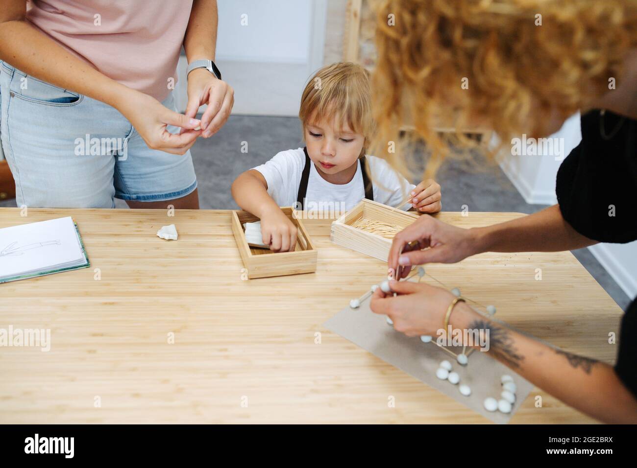 Teachers helping boy to build 3d shapes from plasticine and toothpicks Stock Photo