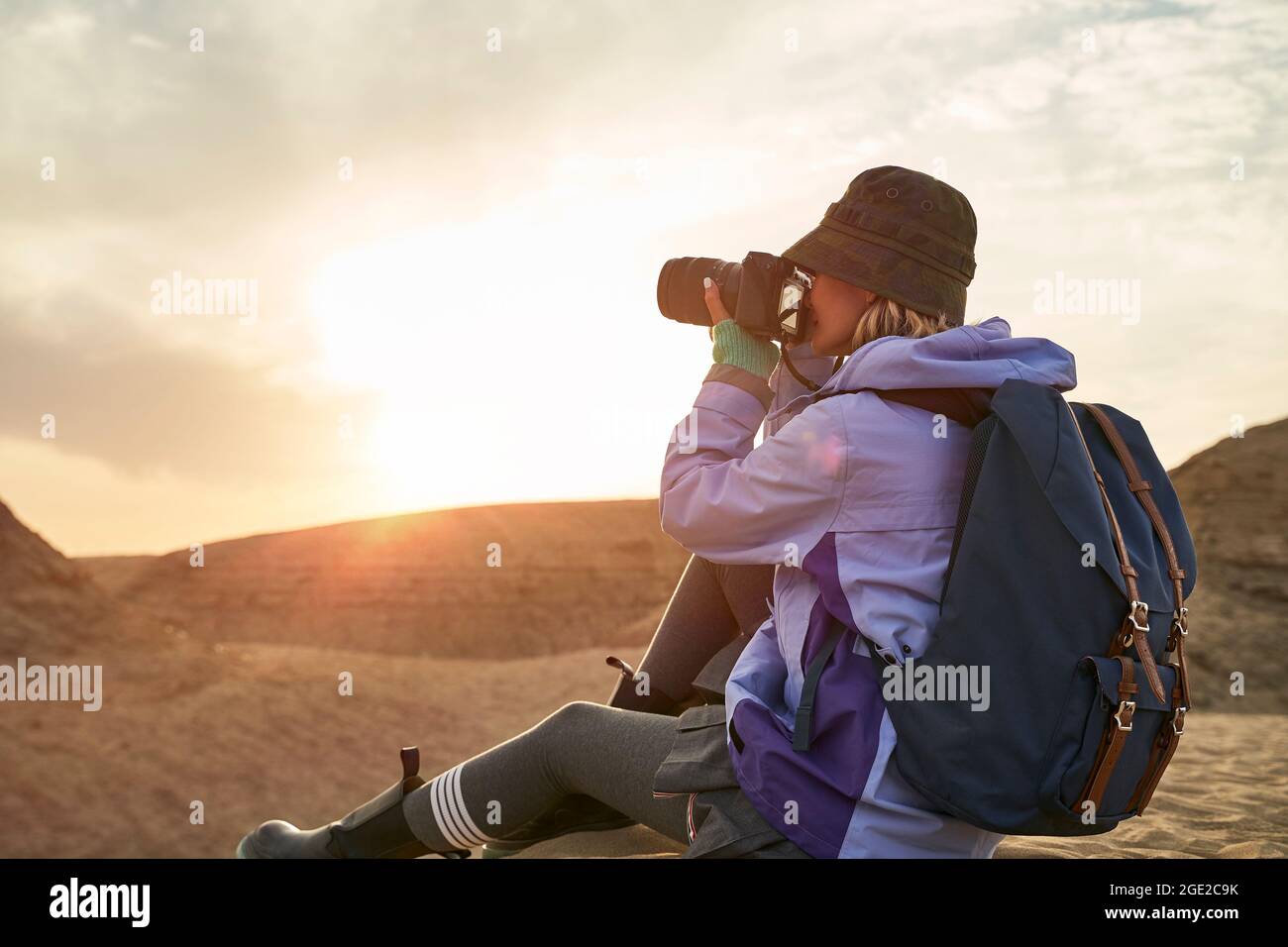 asian woman female photographer taking a photo of landscape in gobi desert with yardang landforms at sunset Stock Photo