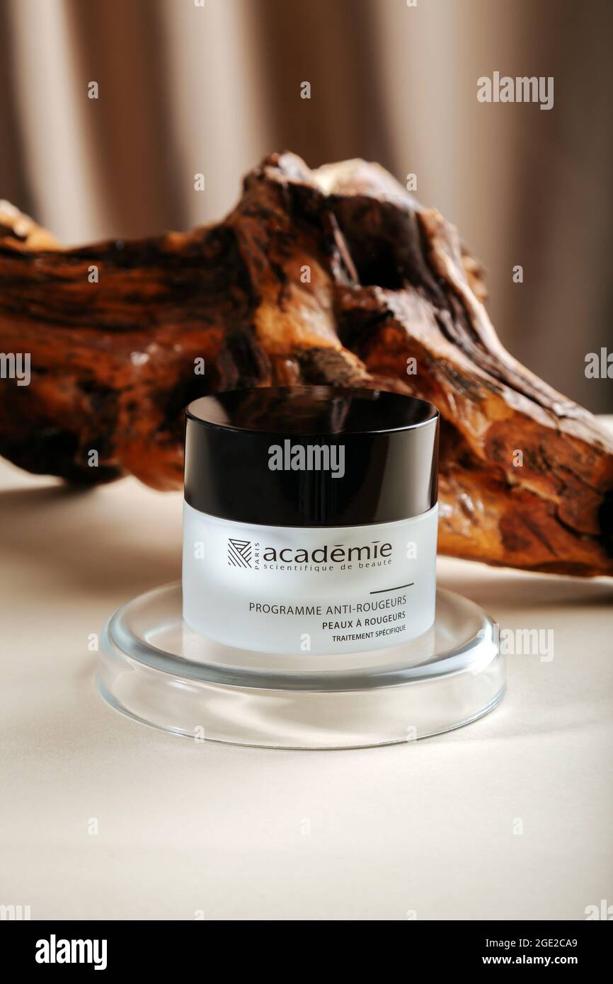 Academie Cream for skin on wooden bark beige background with laboratory