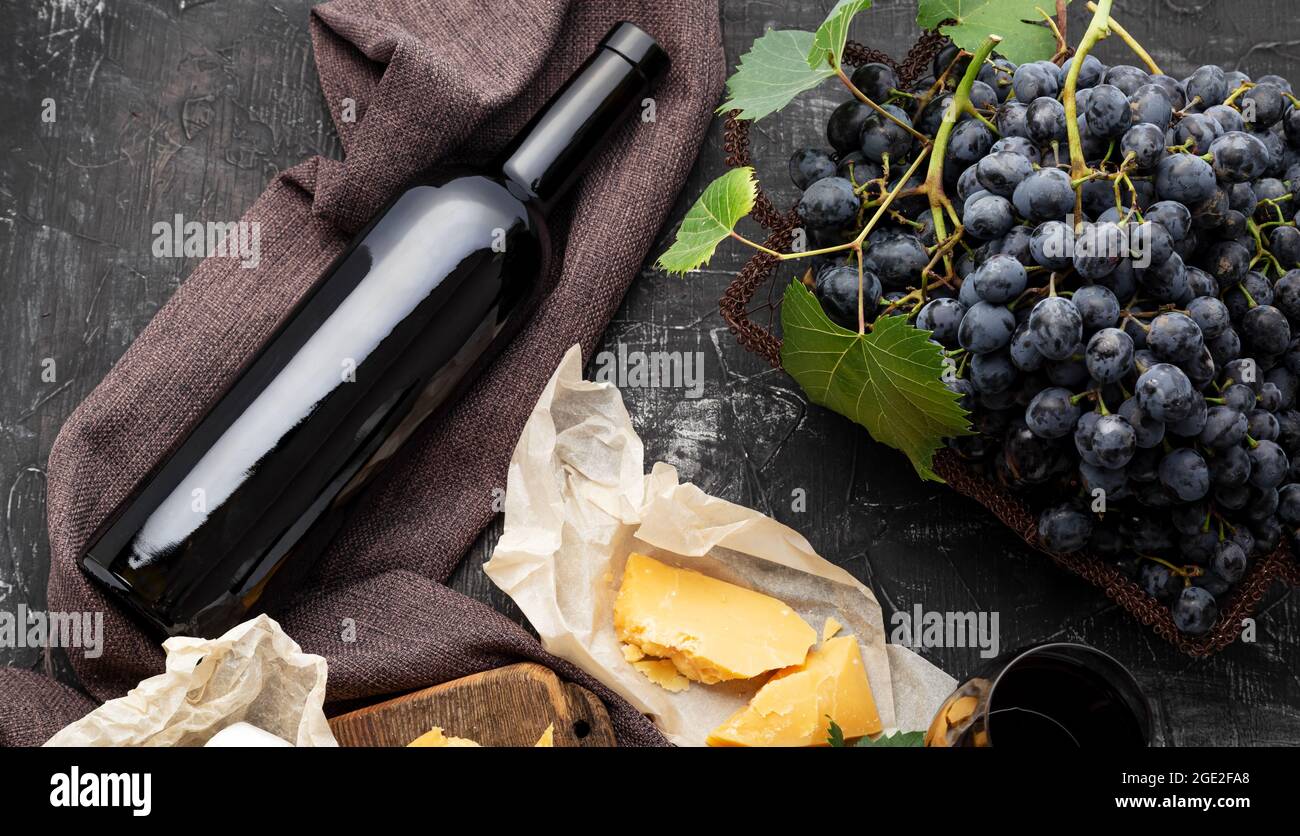 Red wine bottle different cheeses grapes. Vintage still life wine composition with Camembert aged cheese, grapes. Restaurant dinner, wine tasting on Stock Photo