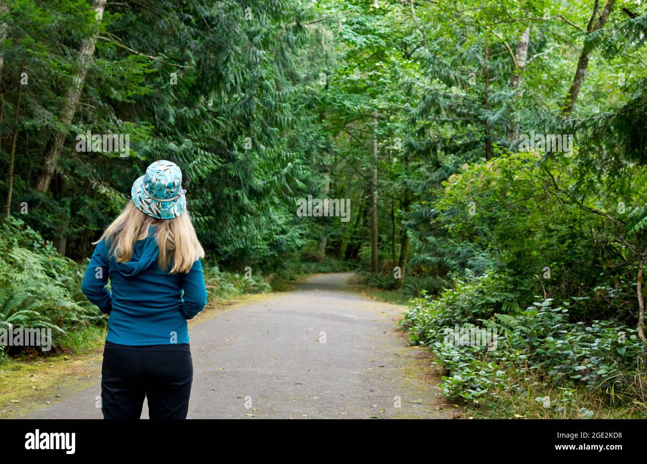 Woman walking on a pathway through the forest on Salt Spring Island, British Columbia, Canada.Salt Spring Island BC Stock Photo