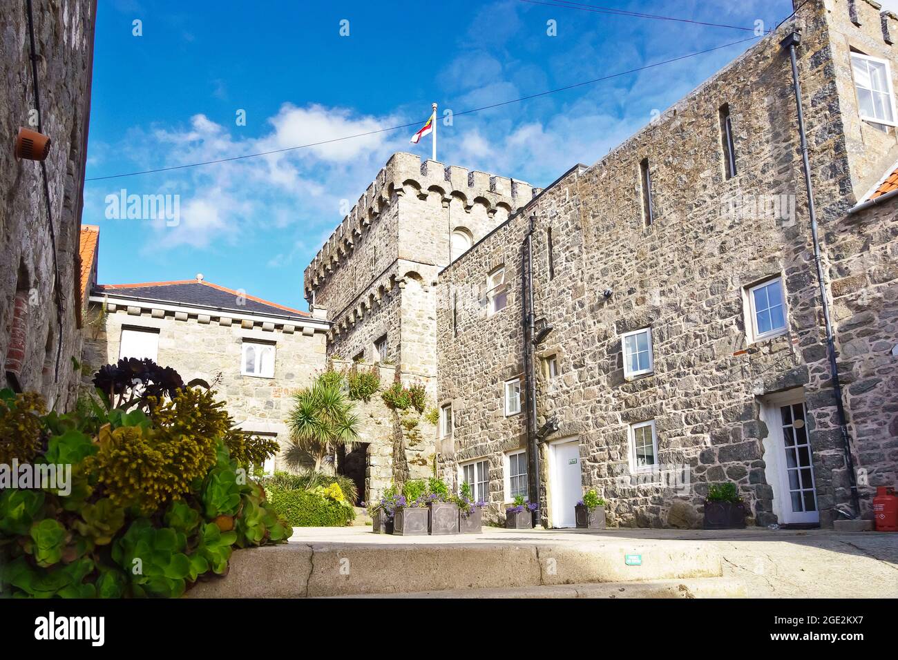 Herm, Channel Islands, UK - July 2, 2016: courtyard in the village with the building housing the Manor Cottage holiday home on a sunny summer day. Stock Photo