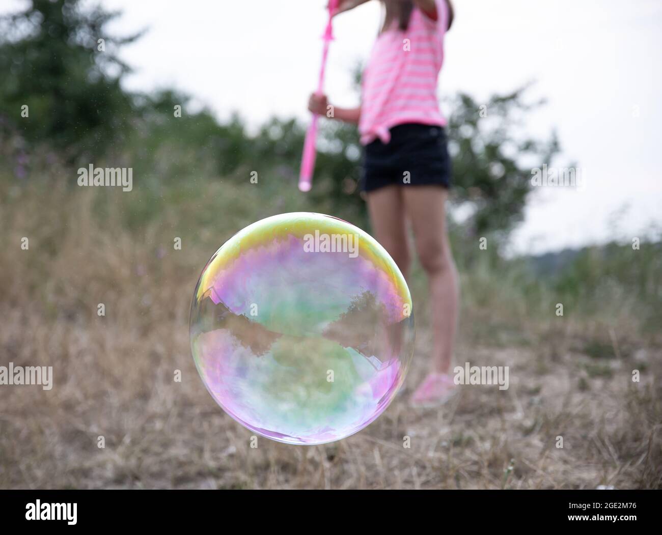 A little girl in nature plays with big soap bubbles Stock Photo - Alamy
