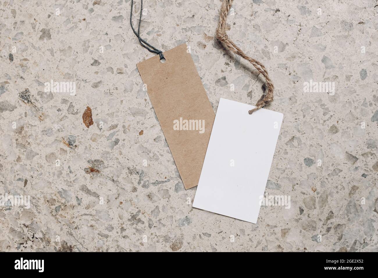 Empty paper gift tags, price labels with ropes on terrazzo background. Marble stone texture. Modern template, branding identity. Summer vacation Stock Photo