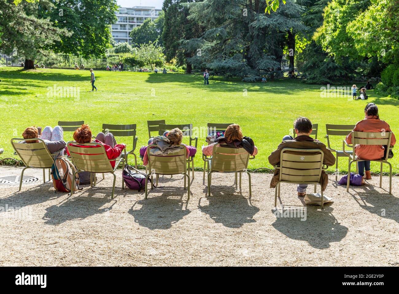 People resting in the sun sitting on chairs in the Luxembourg Gardens in Paris Stock Photo