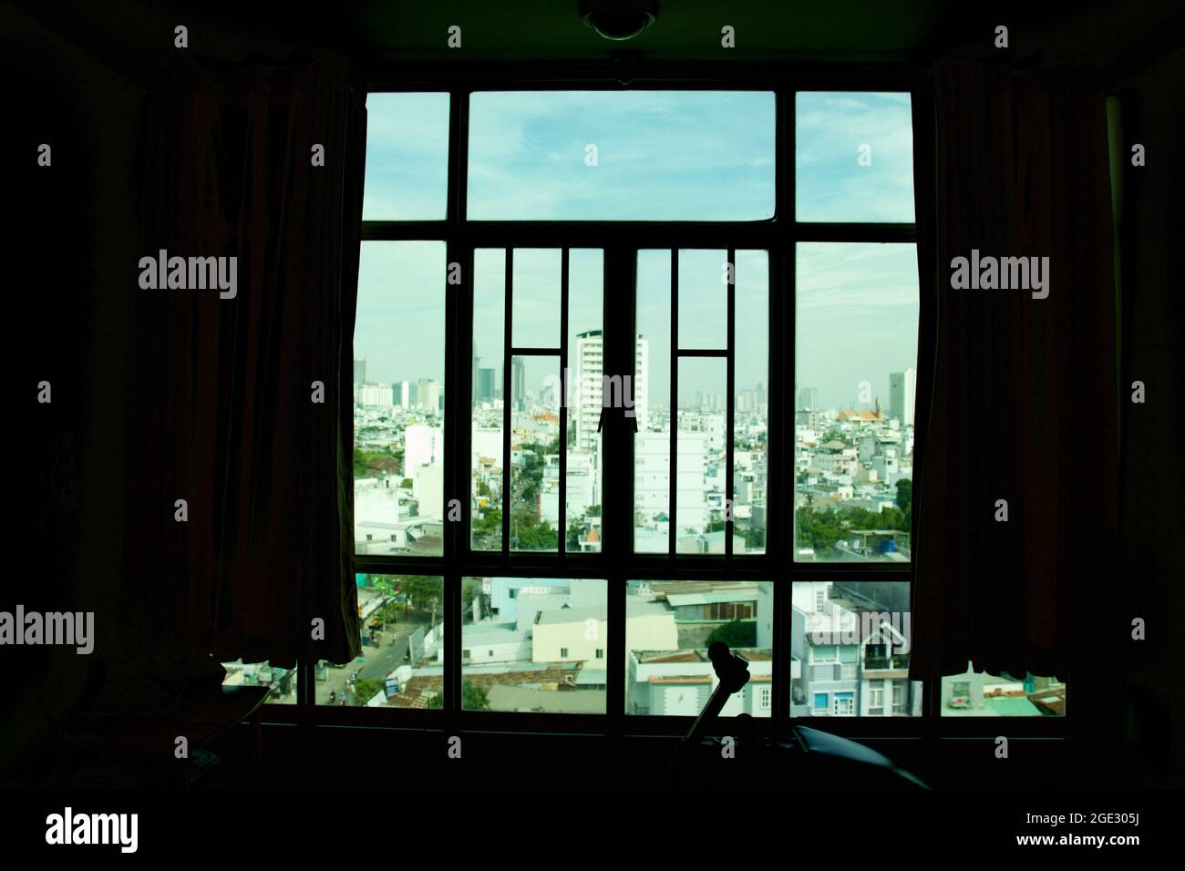 The wind coming through colourful curtains and iron window grilles from the blue sky in Ho Chi Minh City, Vietnam. Stock Photo
