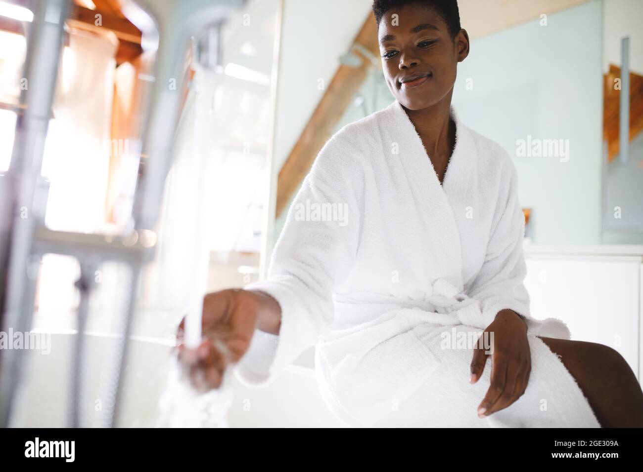 Smiling african american woman in bathroom running a bath Stock Photo