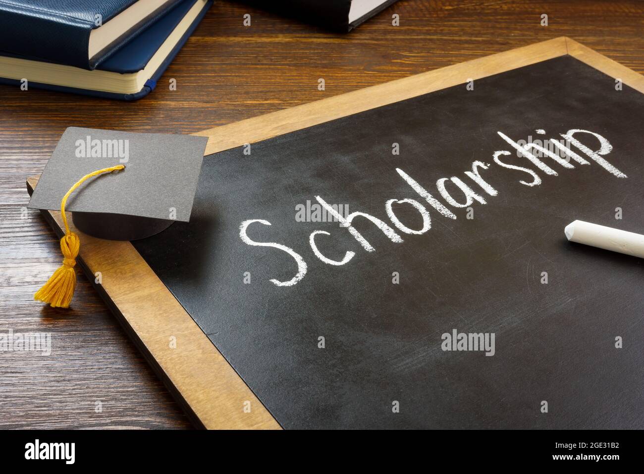 Scholarship written on the blackboard and graduation cap. Stock Photo