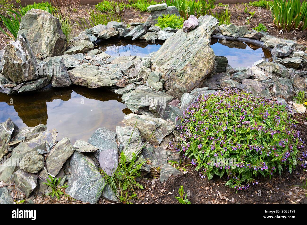 Artificial pond in the garden lined with gray decorative stones Stock