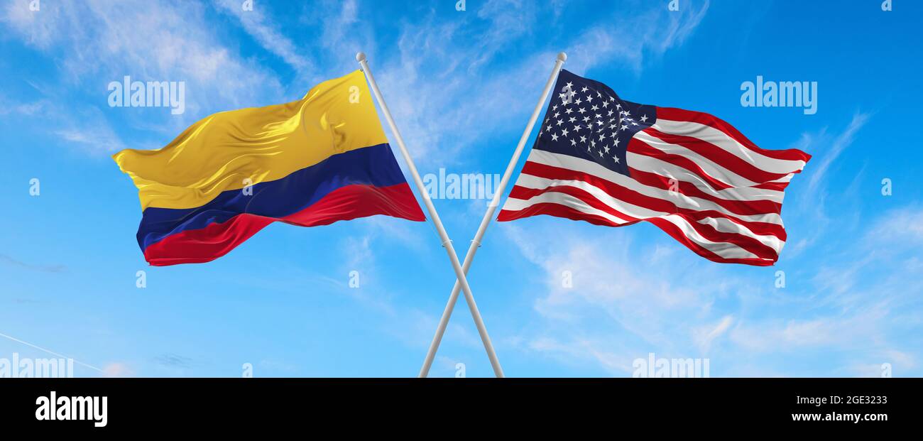 flags of USA and Colombia waving in the wind on flagpoles against the sky with clouds on sunny day. Symbolizing relationship, dialog between two count Stock Photo