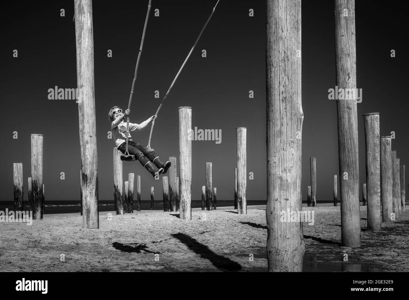 The Netherlands, Petten, Beach. North Sea. Palendorp. Artwork with poles. Boy swinging. Stock Photo