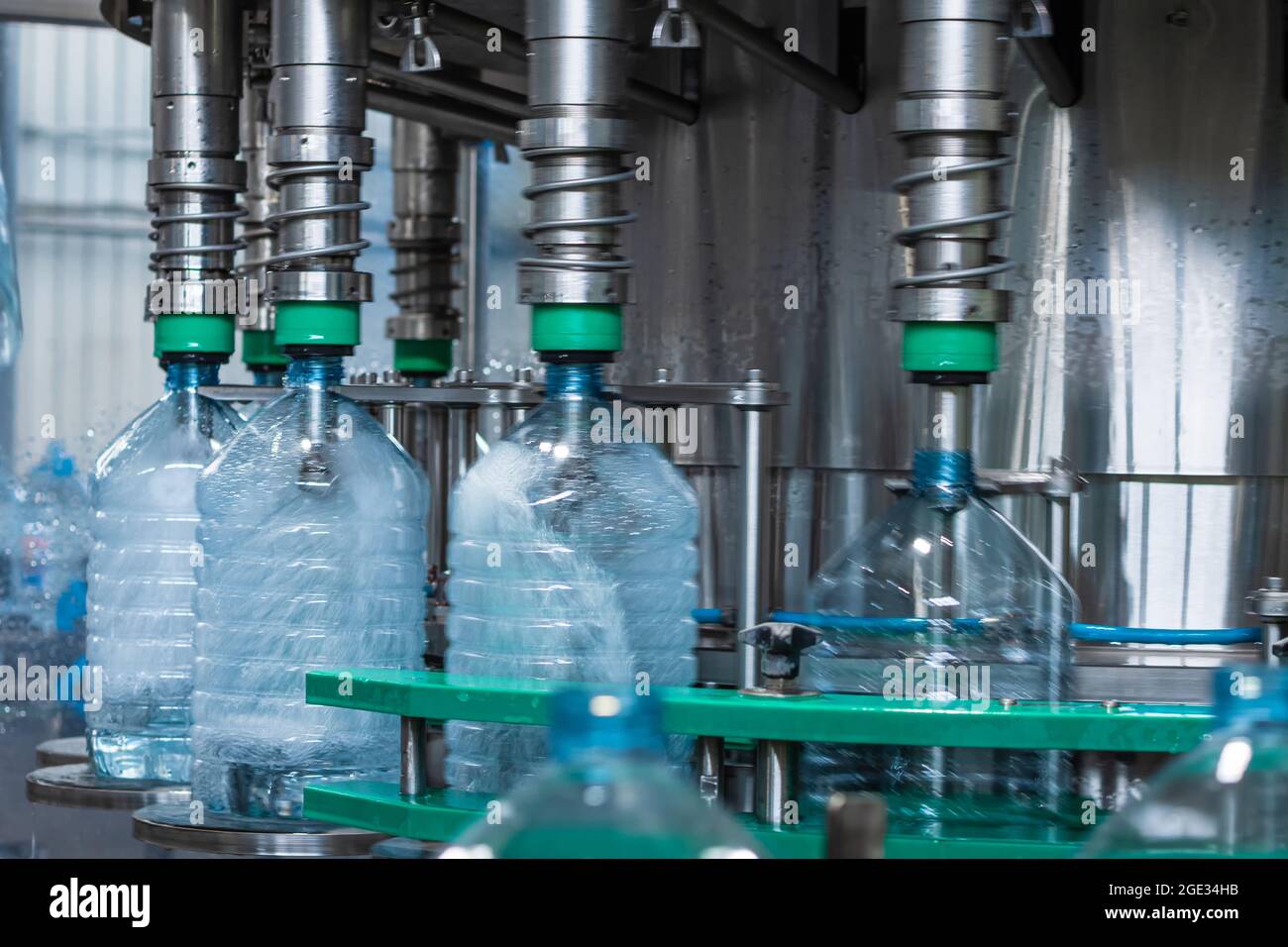 Five-liter plastic bottles in the process of filling with water in a filling machine. Food production Stock Photo
