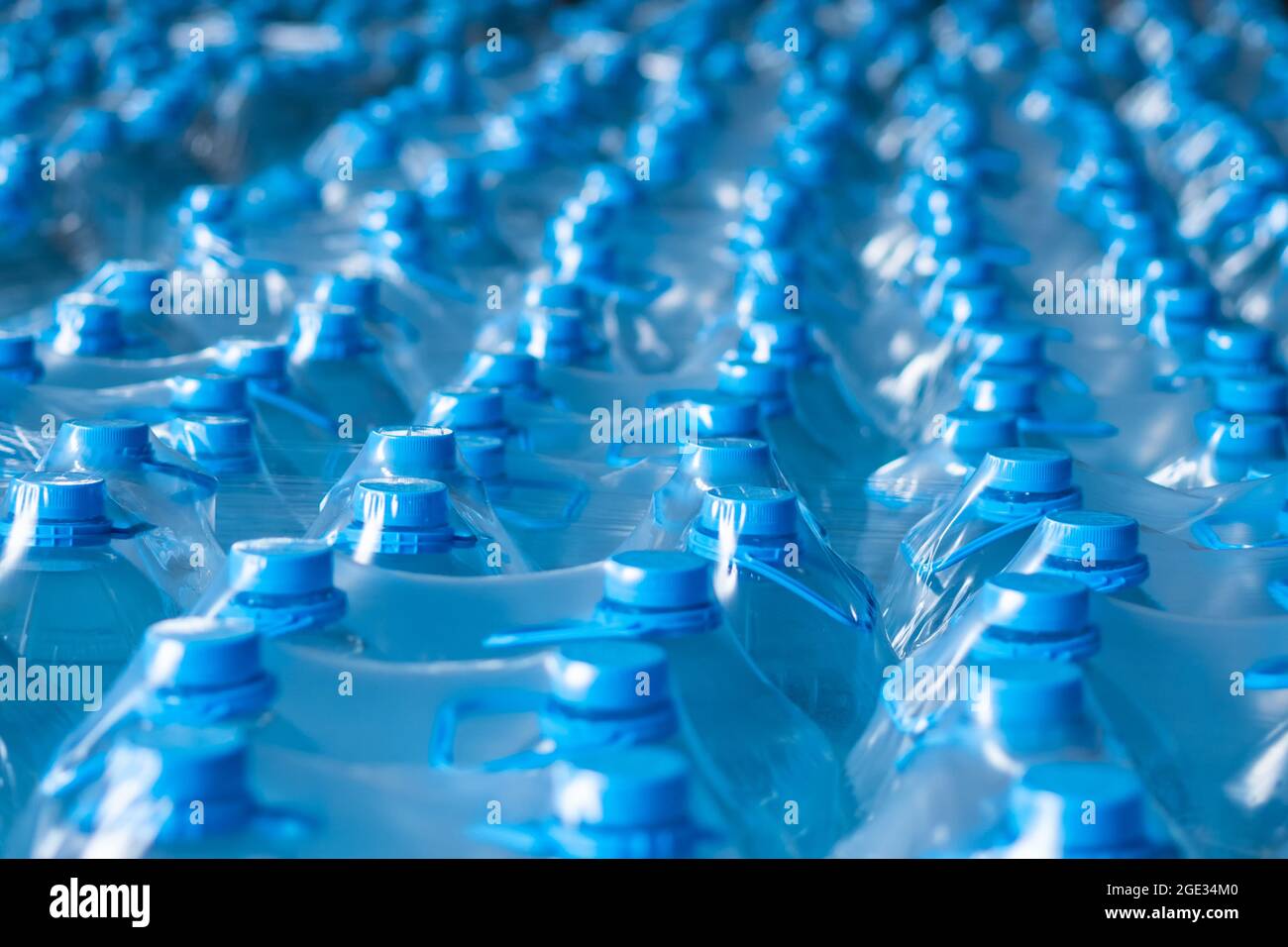 Blue plastic bottles of 5 liters packed in the finished product warehouse. Background image. Food production Stock Photo