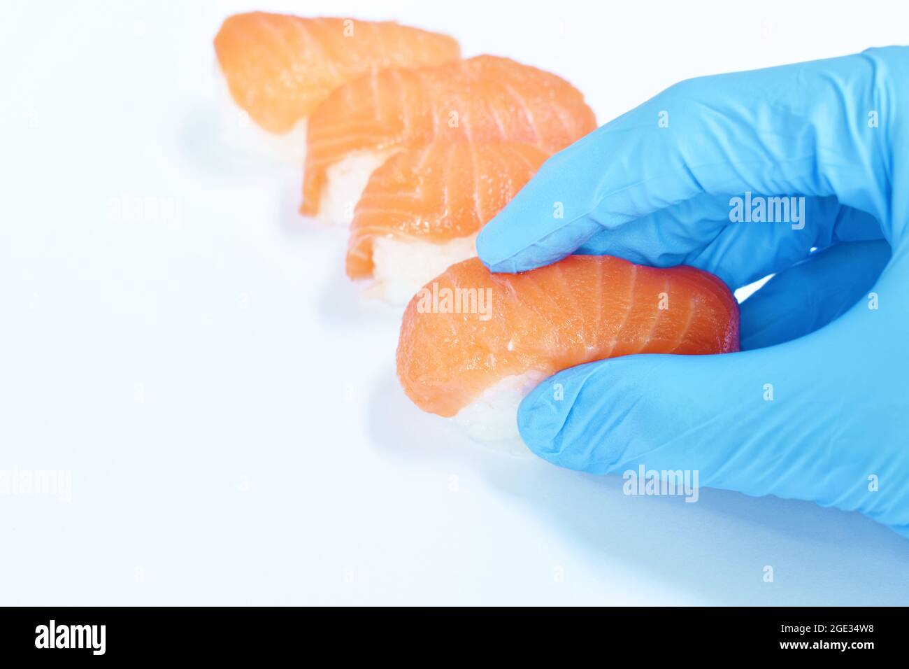 chef hand wear blue glove made salmon Sushi Japanese food with wasabi