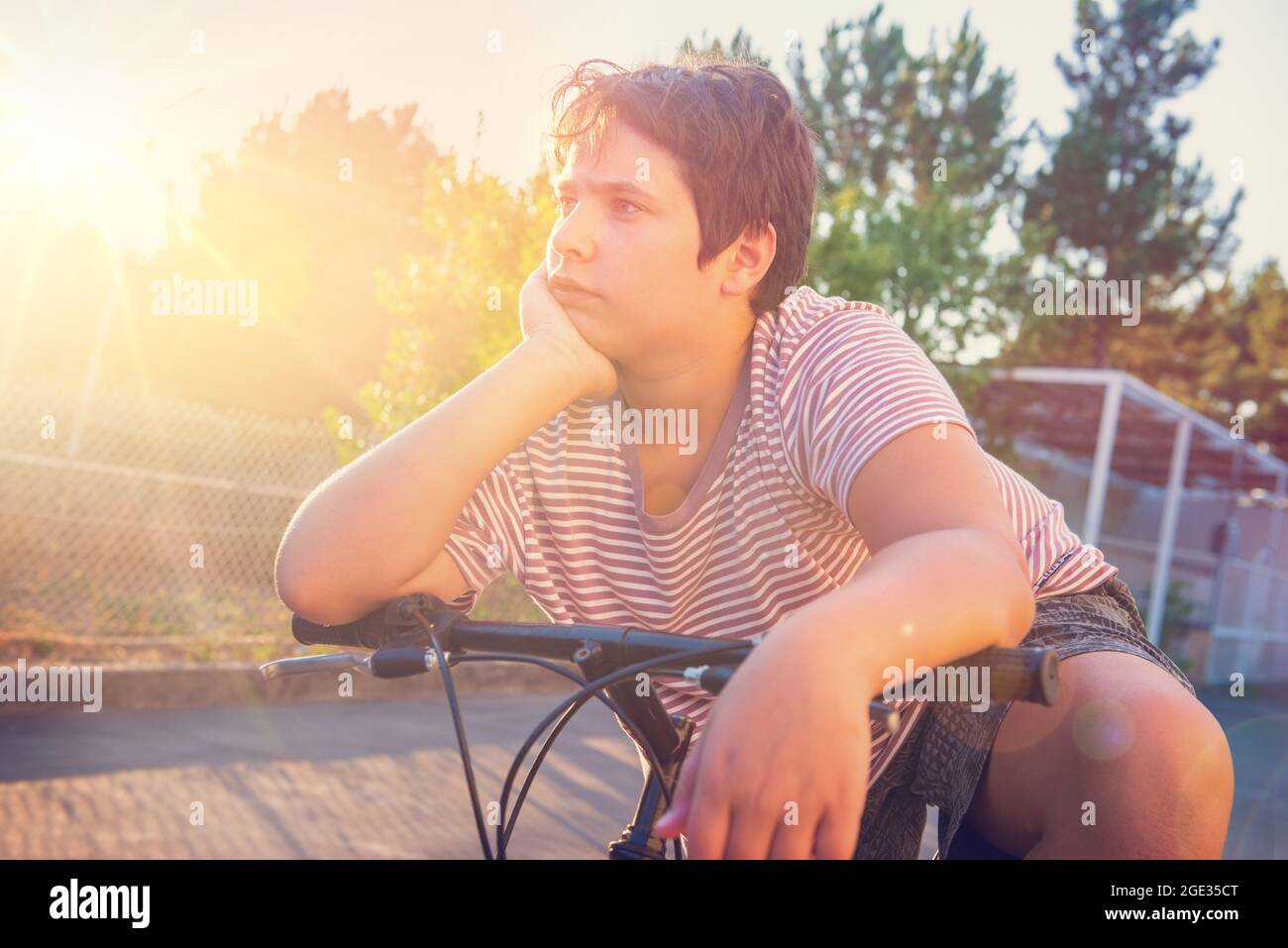 Boy posing in a bicycle outdoors at sunset Stock Photo